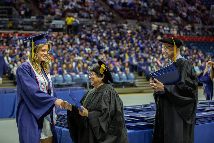 Bandana Purkayastha and Andrew Moiseff, CLAS associate deans, hand out diplomas at the College of Liberal Arts and Sciences (CLAS) Commencement ceremony one at Gampel Pavilion on May 7, 2023.