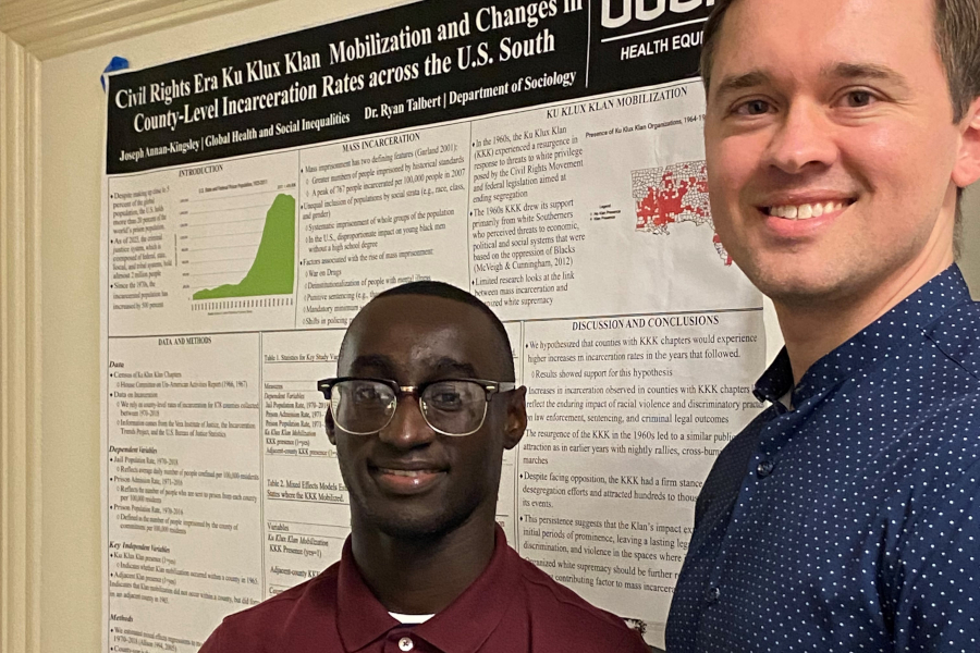 Joseph Annan-Kingsley and faculty advisor Dr. Ryan Talbert stand in front of a research poster that reads "Civil rights Era Ku Klux Klan Mobilization and Changes in County-Level Incarceration Rates across the U.S. South"